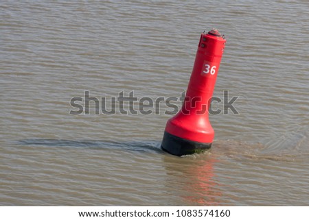 Red buoy as a marker for shipping on the UNESCO protected Wadden Sea in the North of the Netherlands
