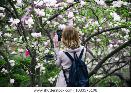 A girl photographs flowers on her mobile phone