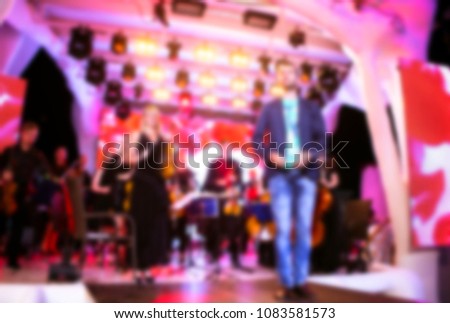 blurred for background night club. Artist performs clubs show with orchestra from stage during concert at nightclub with lights show. Artist on club stage during night party.
