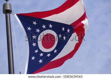 Flag of Ohio waving in the wind with blue sky as background closeup
