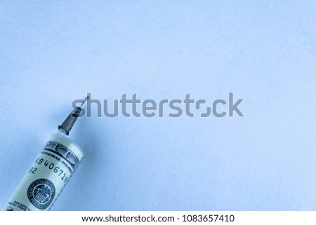 financial injections, money entry: a banknote of  100 inside a syringe for injection, the needle pierces a sheet of paper with free space, toning