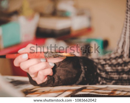 Female artists hand holding big brush. Woman painting picture.