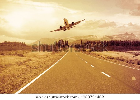 Airplane flying over roadway on background mountains and cloudscape 