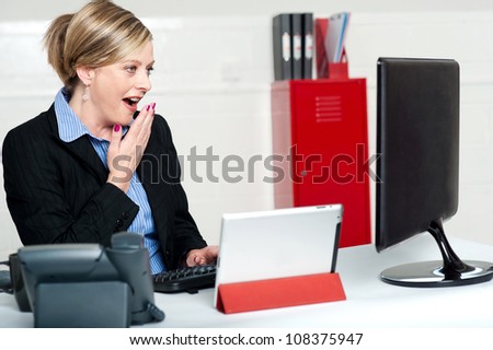 Surprised female secretary looking at lcd screen. Indoors office shot