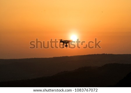 silhouette of flying drone in glowing red sunset sky