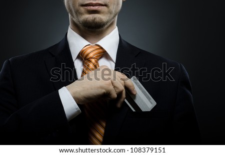 businessman in black costume and orange necktie put or take out credit card in pocket, close up
