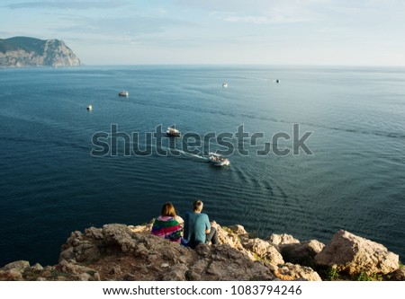 Two people on the beach admire passing by boats and sunset