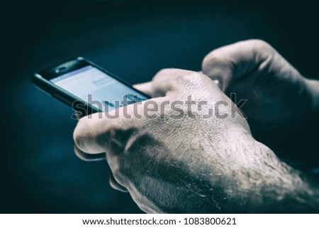 A man holding a smartphone in a dark room