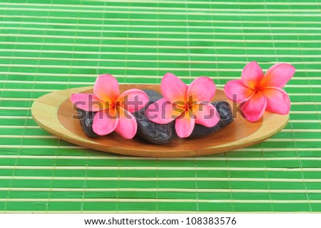 Frangipani and polished stone on bamboo mat