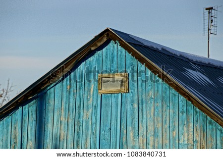 The top of a blue wooden wooden house with a small window
