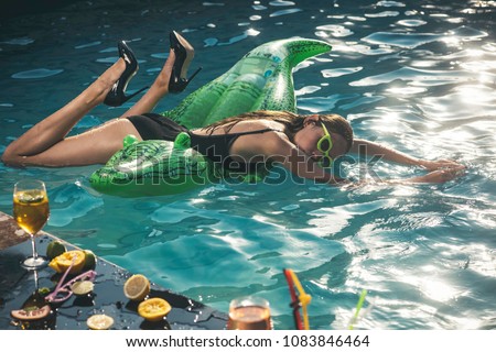 woman with inflatable mattress in a crocodile shape going to swim. On holidays having fun and relaxing at the beach.