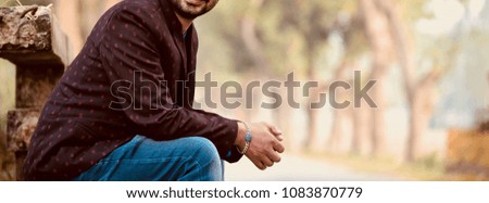 Man sitting around a place wearing stylish jeans wear and bracelets isolated unique photo