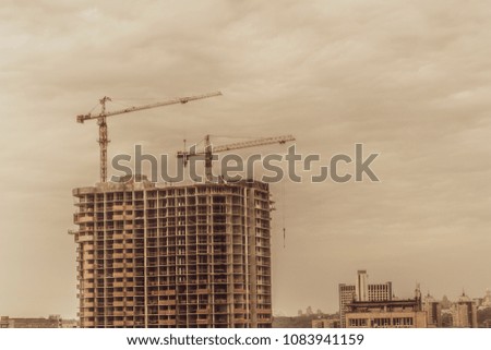 Building cranes and building under construction stylized photo.