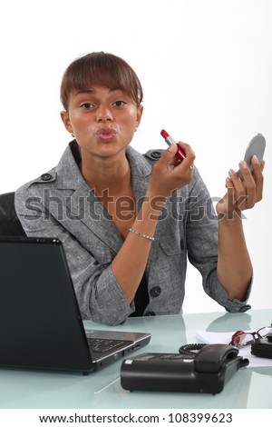 Woman applying lipstick at the office