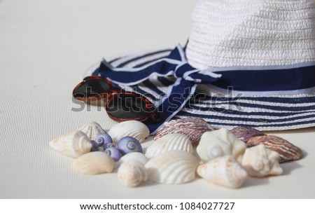 Summer background - sea life style objects over white background - white and blue straw hat sunglasses & sea shells. Copy space. Hello Summer concept