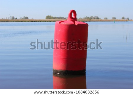 Red buoy in netherlands waterway photo taken on a sunny day with a beautiful blue sky
