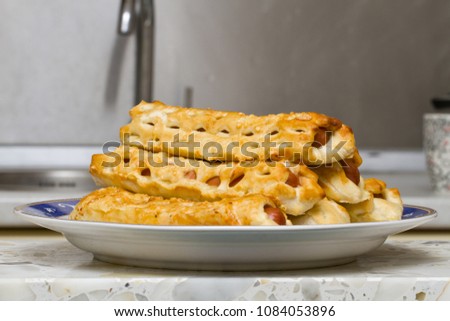 Appetizing sausages in a dough with a cheese ruddy crust.
