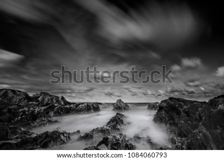 Long exposure seascape and rocky beach in black and white. Nature composition. A slow shutter speed was used to see the movement ( Soft focus due to long exposure shot )