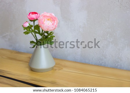 Pink and white peonies in a vase on a wooden table.