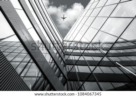 Flying airplane over modern architecture building, low angle black and white high contrast picture 