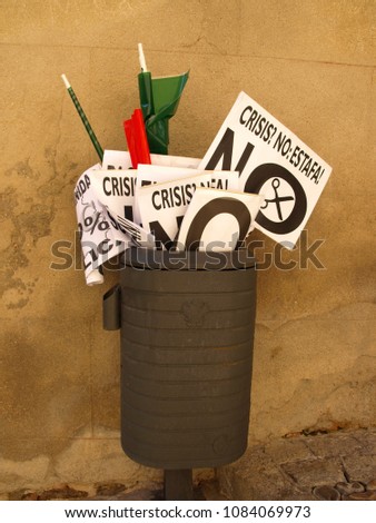 Small banners used in a demonstration of officials end up in a wastebasket, in Toledo, Spain. Translation: Crisis not: scam. No cuts
