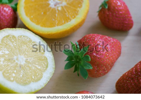 Strawberries, lemon and orange on a wooden board