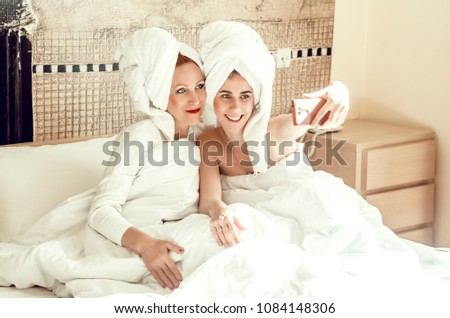 mom and daughter. love and care. girls in the towels at home make a photo on the phone for memory. house.