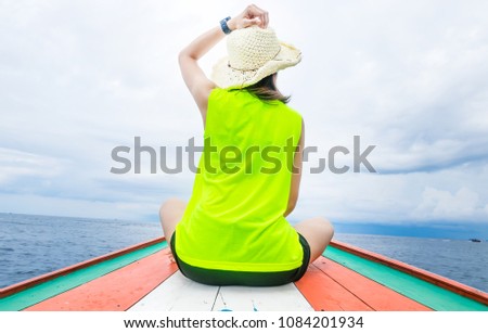 Back view of the young woman wear hat in relax outside on the boat and looking at the sea view.
