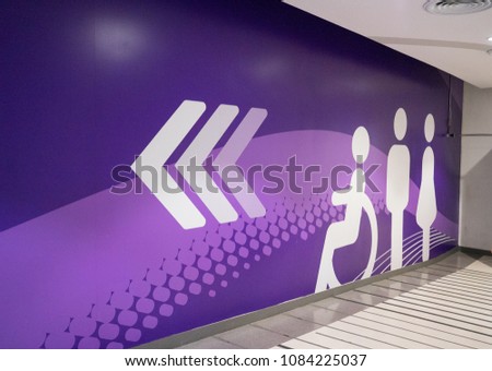 Toilet direction sign with triple arrow, painted on cement wall of department store, luxury shopping center, ultra violet tone. Sign idea for interior concept.