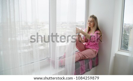 youth leisure. selfie time. online photo sharing lifestyle. young girl sitting on a windowsill taking photo