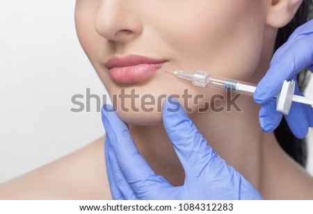 The doctor cosmetologist makes Lip augmentation procedure of a beautiful woman in a beauty salon.Cosmetology skin care. Royalty-Free Stock Photo #1084312283
