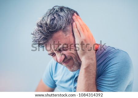 male having ear pain touching his painful head isolated on gray background Royalty-Free Stock Photo #1084314392