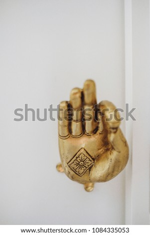 Buddha hand sign for ok, with a flower in the palm of the hand in a diamond shape box. 