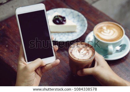 Close-up image of woman or male hands using smartphone at cafe while drinking coffee. Typing text message, via cell phone, Social networking concept. Smartphone mockup.