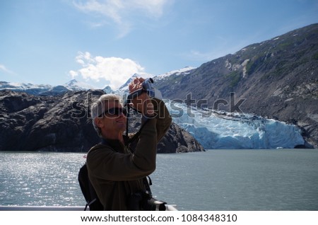 A happy backpack traveller takes a lot of photos of glacier. Portage Glacier. Alaska. USA.