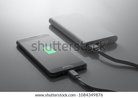 the phone is charged from the powerbank, in dark tones, 100% charge