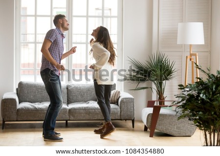 Young romantic carefree couple in love dancing spending time together at home, cheerful smiling man and woman having fun in cozy modern living room, happy husband and wife enjoying weekend Royalty-Free Stock Photo #1084354880