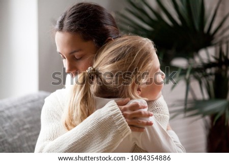 Loving mother hugging cute little girl, young woman embracing adopted child holding tight, sincere warm relationships between mum and daughter cuddling, moms love and care or adoption concept Royalty-Free Stock Photo #1084354886