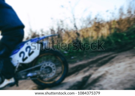 Blurred motocross racer accelerating in dirt track on the mountain motocross race in dirt track in day time. Blurred background with bokeh effect.  