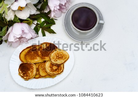 tea and pancakes on the background of beautiful pions.