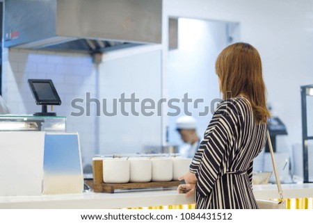 Woman wait for an order at desk on food court in mall