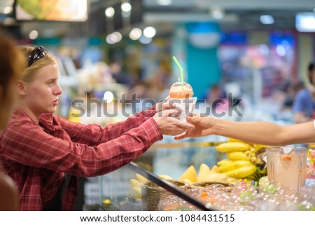 Customer buy fruit drink on food court holding plastic cup with straw