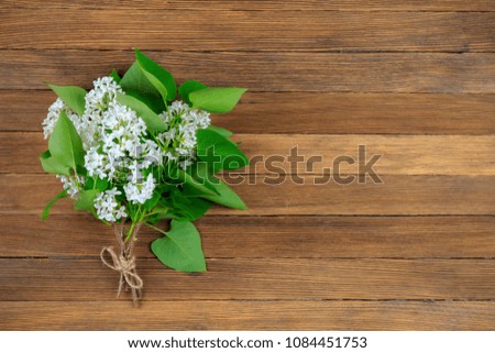 bouquet of white lilac flowers with green leaves on vintage wooden retro background with copy space