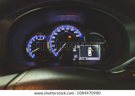 Picture of sport Eco-car dashboard. The speedometer shows signal warning that hand brake is pulled up. Multi-function Information Display on the right shows the driver's door is opening.