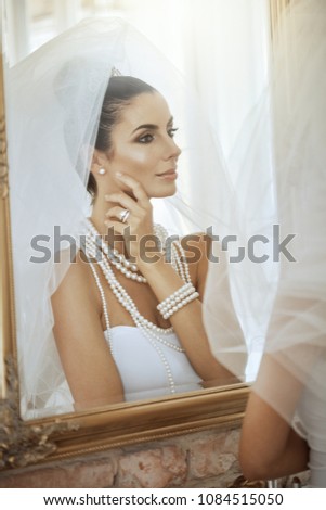 Beautiful young bride front of mirror in full glamour.