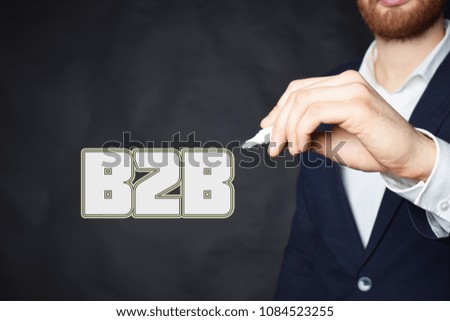 The businessman writes an inscription with a white marker:B2B