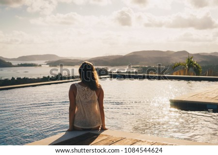 Woman is sitting at a pool at a breathtaking landscape