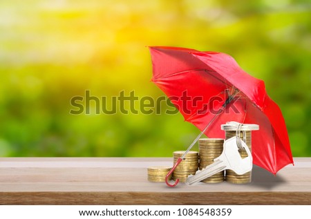 Coins with keys under a red umbrella protection money or business concept