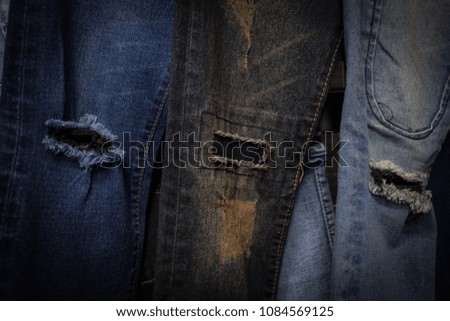 Hole and Threads on Denim Jeans. Ripped Destroyed Torn Blue jeans background. Close up blue jean texture