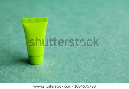 Blank green cosmetic tube on green background. Simple plastic container, mock up packaging design. shallow depth of field, copy space photography